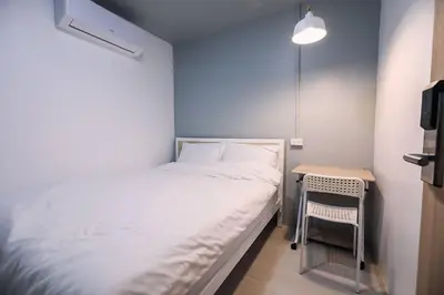 a small bedroom with a bed and a small table at LCT Hostel Bangkok in Bangkok