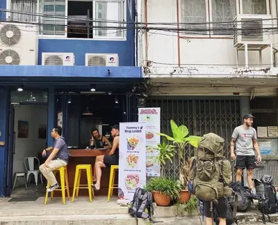 a group of people sitting outside of a restaurant at LCT Hostel Bangkok in Bangkok