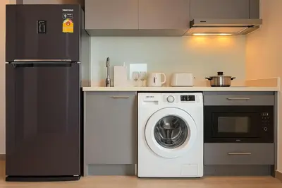 a kitchen with a washing machine and a refrigerator at Thonglor Next to BTS Modern Condo - Fitness gym with full view in Bangkok