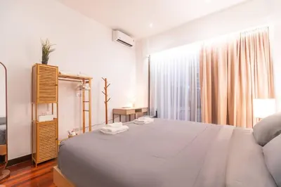 a white bedroom with a large bed and a window at Minimal House Maximum Happiness in Thung Maha Mek