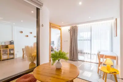 a living room with a table and a large window at Minimal House Maximum Happiness in Thung Maha Mek