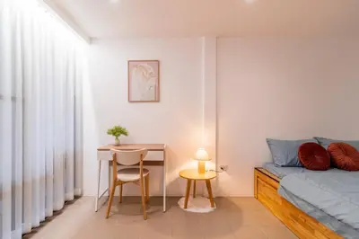 a bedroom with a bed and a table and a desk at Minimal House Maximum Happiness in Thung Maha Mek