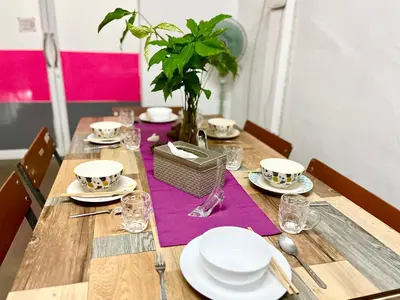 a wooden table with plates and glasses and a plant at Anne & Tan Stylist Homestay in Bangkok