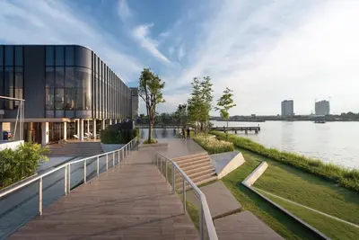 a walkway next to a building next to a body of water at The Politan Aqua, River Front in Ban Sai Ma