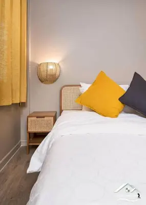 a bedroom with a white bed with yellow and blue pillows at Delightful Townhouse in the Heart of Sukhumvit in Bangkok