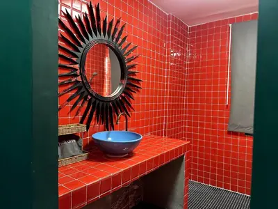 a red tiled bathroom with a blue sink and a mirror at Delightful Townhouse in the Heart of Sukhumvit in Bangkok
