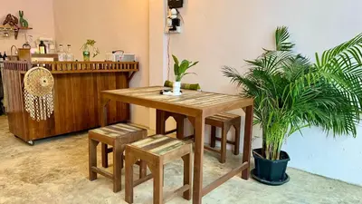 a wooden table and stool in a room with plants at Baan YentaFo - Pink House in Talad Noi in Chinatown