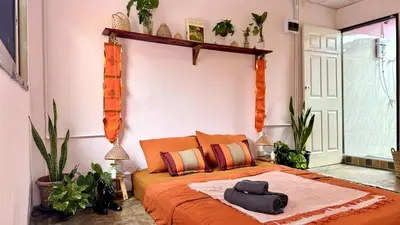 a bedroom with a bed with an orange blanket at Baan YentaFo - Pink House in Talad Noi in Chinatown