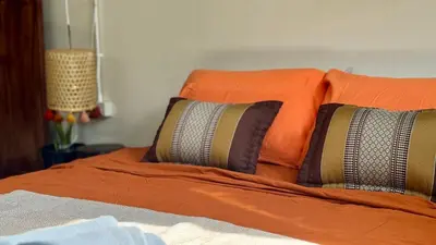 a bed with orange sheets and pillows on it at Baan PadSeeEw - Rooftop Riverview in Khlong San