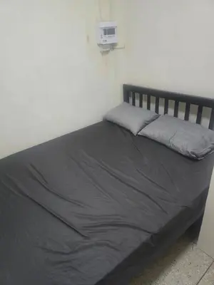 a bed in a room with a gray blanket on it at Cozy bangkok hostel in Bangkok
