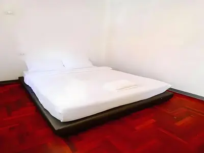 a white bed in a room with a wooden floor at XX GO INN Silom - BTS Surasak in Yan Nawa