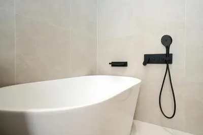 a white bath tub in a bathroom with a shower head at day one space - BTS On Nut - Live Above Cowork Cafe in Bangkok