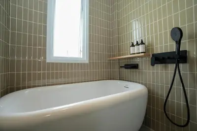 a white bath tub in a bathroom with a window at day one space - BTS On Nut - Live Above Cowork Cafe in Bangkok