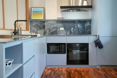 a kitchen with white cabinets and a black appliance at day one space - BTS On Nut - Live Above Cowork Cafe in Bangkok