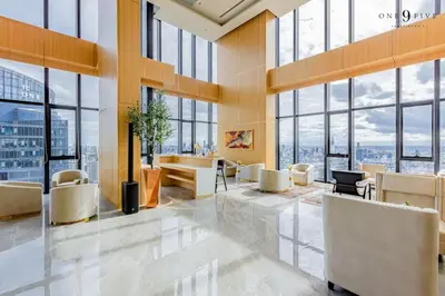 a lobby with chairs and tables in a building with windows at 47fl Skyview with Balcony Pool Gym 200m from MRT in Bangkok