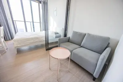 a living room with a couch and a table and a bed at High Skyview Studio with Desk Pool Gym MRT 200m in Ban Na Song