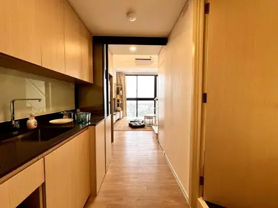 a kitchen with wooden cabinets and a long hallway at High Floor Loft with Pool and Gym in Ban Na Song