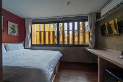 a bedroom with a bed and a large window at Wat We See Bangkok Hostel in Bangkok