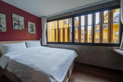 a bedroom with a bed and a large window at Wat We See Bangkok Hostel in Bangkok