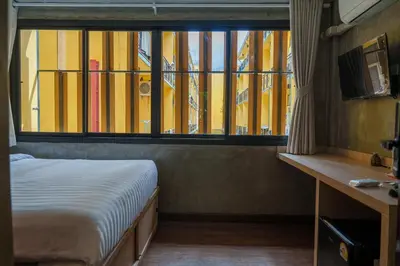 a bedroom with a bed and a large window at Wat We See Bangkok Hostel in Bangkok