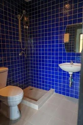 a blue tiled bathroom with a toilet and a sink at Wat We See Bangkok Hostel in Bangkok