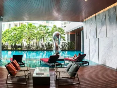 a pool with three chairs and two laptops on a table at The room, luxury condo 21fl 1 Bedroom ,near bts in Bangkok