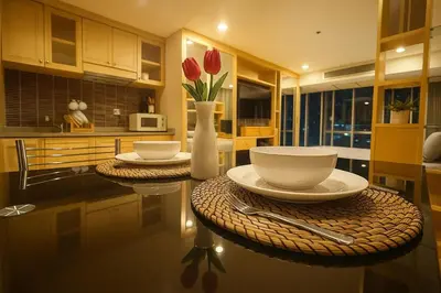 a kitchen with two tables and a vase with red flowers at Modern Suite near BTS Nana Netflix Sky View in Makkasan
