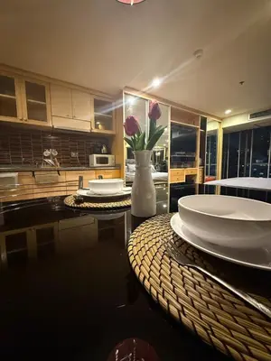 a kitchen with a table with plates and a vase of flowers at Modern Suite near BTS Nana Netflix Sky View in Makkasan