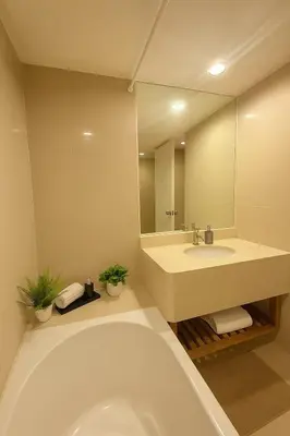 a bathroom with a tub and a sink and a mirror at Modern Suite near BTS Nana Netflix Sky View in Makkasan