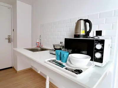 a kitchen counter with a microwave and a bowl at Komfort Duplex BTS Ratchayothin in Bangkok