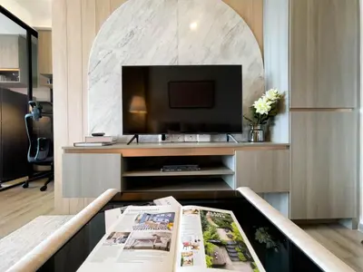 a living room with a tv and a newspaper on a table at Near BTS Bearing l Rooftop pool and gym in Bangkok