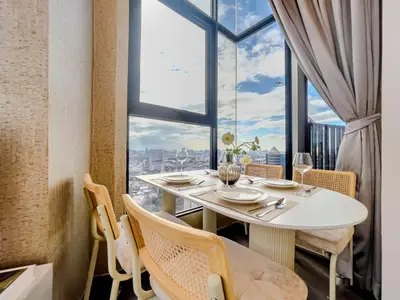 a dining room with a table and a large window at Duplex near BTS l Rooftop Pool l Skyline l Sontana in Bangkok