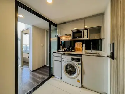 a kitchen with a washing machine and a microwave at Duplex near BTS l Rooftop Pool l Skyline l Sontana in Bangkok