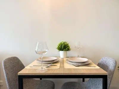 a wooden table with two wine glasses and a plant at Near BTS - Near Iconsiam - Pool and Gym - Sontana in Bangkok
