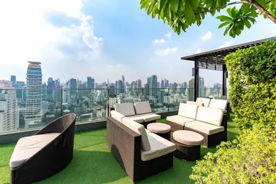 a rooftop patio with furniture and a view of the city at Free Airport Pick Up Rooftop Pool Gym near BTS Emquartier Shopping city center in Bangkok