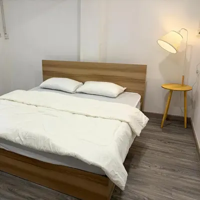 a bedroom with a bed with white sheets and a table at Box me in Bangkok