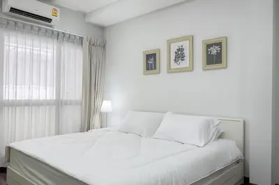 a white bedroom with a white bed and a window at Blissful Heaven Residence at BTS Phromphong Emdistrict Shopping Area in Bangkok