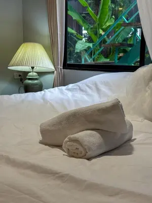 a towel laying on a bed with a window at Pridi cozy home with good location Type A in Bangkok