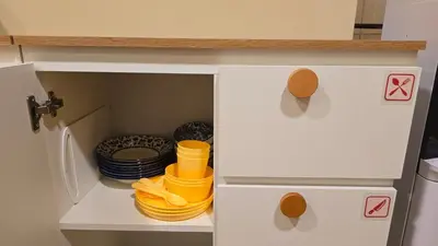 a cupboard with plates and dishes in a kitchen at Postel Chinatown in Bangkok