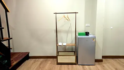 a small refrigerator in a room with a shelf at Postel Chinatown in Bangkok