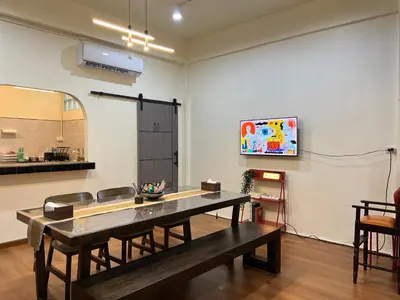 a dining room with a table and a tv on a wall at Baan29 in Bangkok