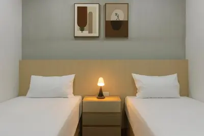 two beds in a room with a lamp on a night stand at City Pause Hostel in Sathani Bang Su