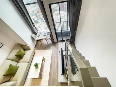 a living room with a couch and a staircase at 250m BTS l Duplex Unit l Rooftop Pool l Sontana in Bangkok