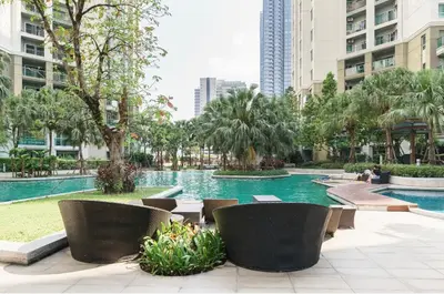 a swimming pool with chairs and trees and buildings at Sky Apartment - Pool - BTS - Gym - Sauna in Bangkok