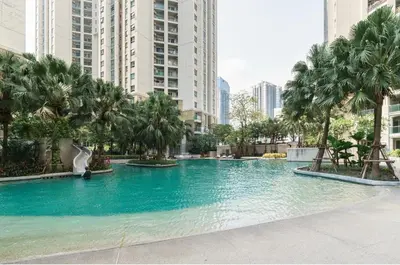 a large swimming pool with palm trees and buildings at Sky Apartment - Pool - BTS - Gym - Sauna in Bangkok
