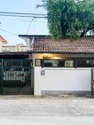 a white building with a gate and a tree at Pridi cozy home with good location Type C in Bangkok