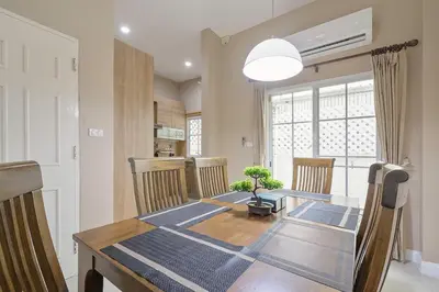a dining room table with chairs and a large window at Modern 3BR Rama Mansion Near Airport plus Amenities in Sathani Ban Hua Mak