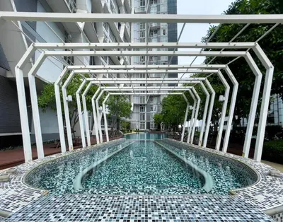 a swimming pool with a tile floor and a building at 150m to BTS l Workspace l Pool and Gym l Sontana in Bangkok
