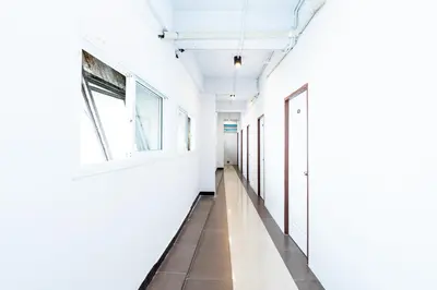 an empty hallway with white walls and windows at The Hidden Khaosan Bangkok in Bang Bua Thong Railway Station