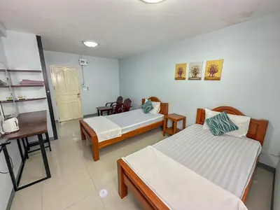 a room with two beds and a table and a desk at Nuanchan Apartment in Ban O Pao